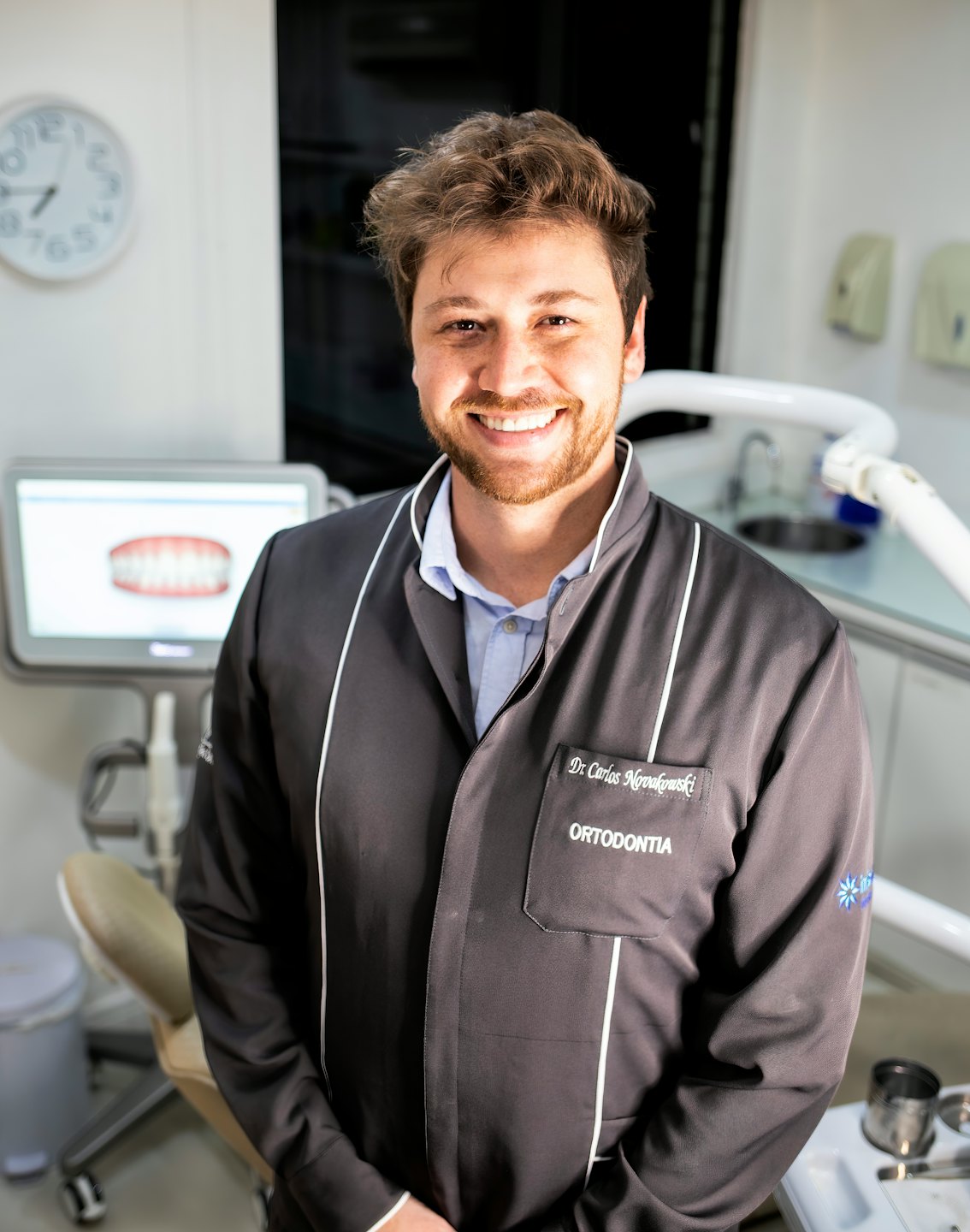 Smiling dentist in a modern dental clinic examines a 3D model.