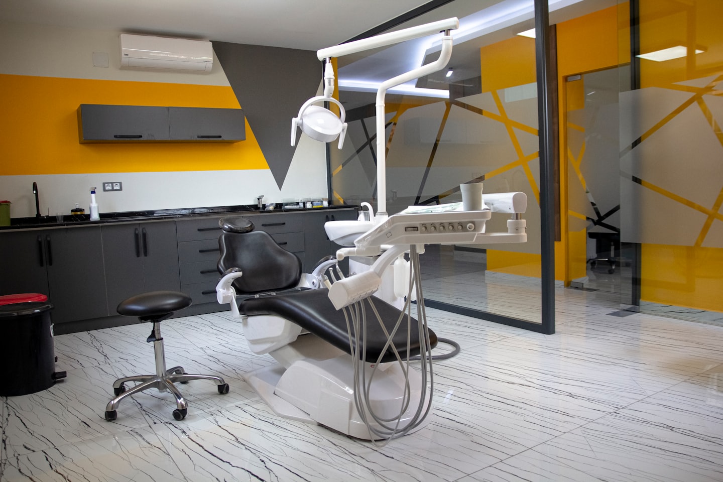 Empty dental treatment room with modern equipment and yellow wall.