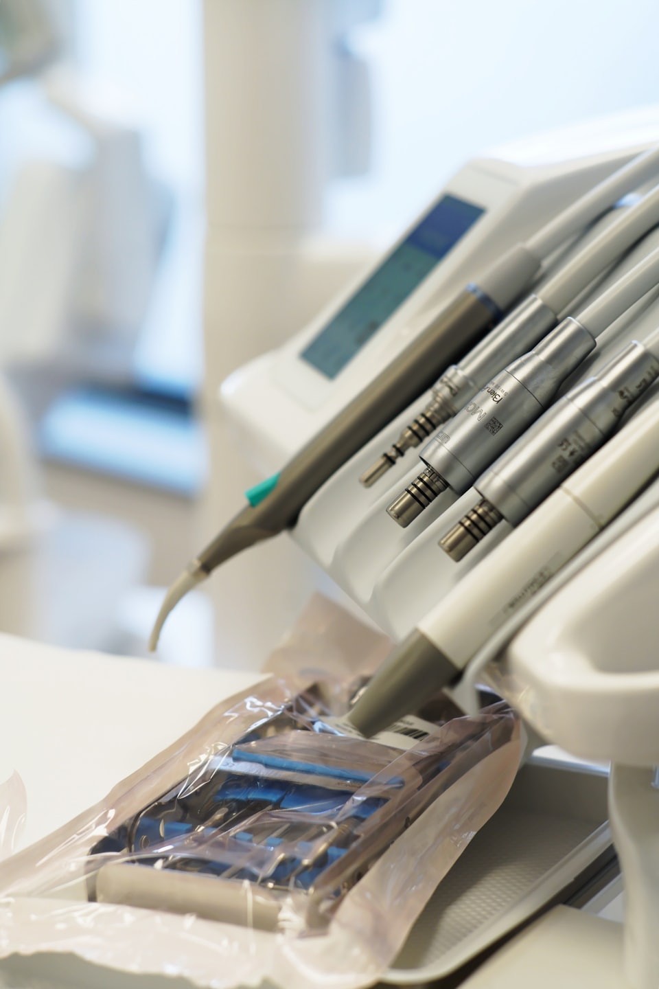 Professional dental handpieces and sterilized instruments on a dental unit.