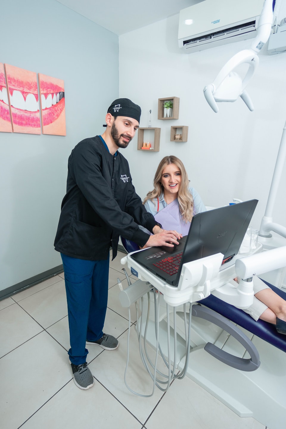 Dentist points to laptop screen explaining treatment to patient.